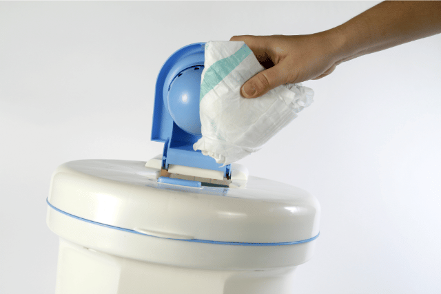 a person disposing of a nappy in a bin