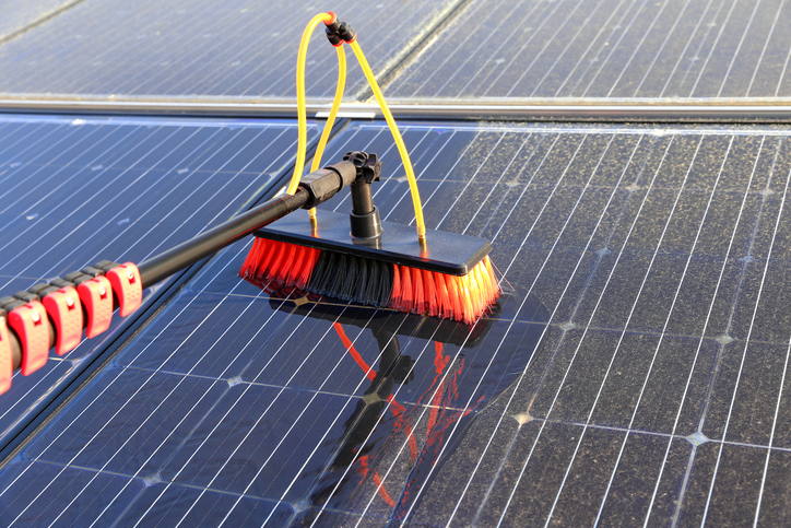 person cleaning solar panels on a rooftop